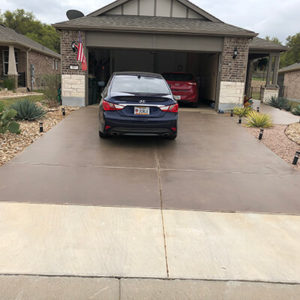 View on the garage of an Austin, TX home before and after the driveway resurfacing.