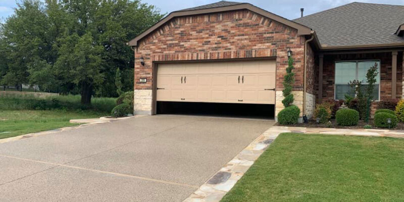 Concrete overlay driveway outside a home in Austin, TX bordered by front lawns.