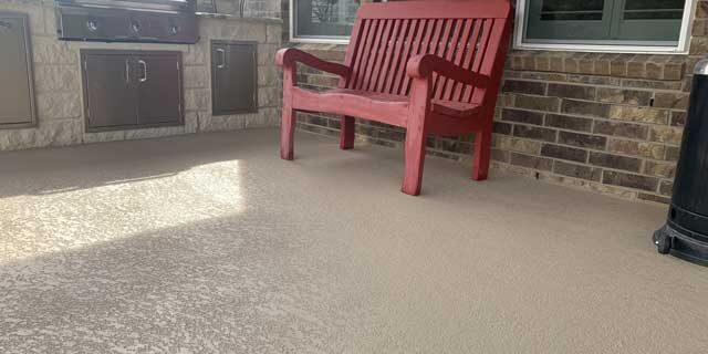 A rustic color bench on a refinished concrete patio outside a home in Austin, TX.