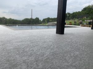 Grey-colored resurfaced concrete around a pool in an Austin, TX home.