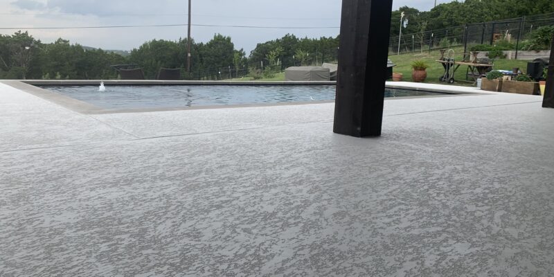 Grey-colored resurfaced concrete around a pool in an Austin, TX home.