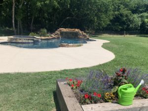Pool deck refinishing work surrounded by a lush green lawn outside a home in Austin, TX.