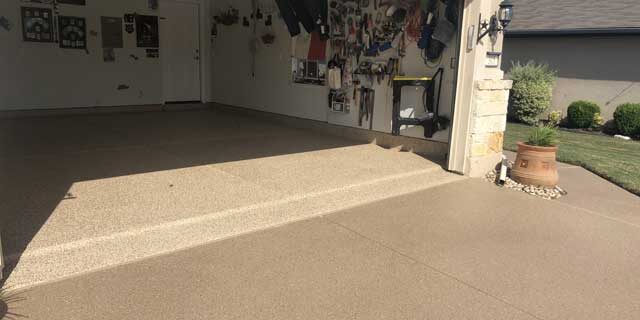 Image of a house with an open garage door and plants; garage floor coating is done over the flooring.