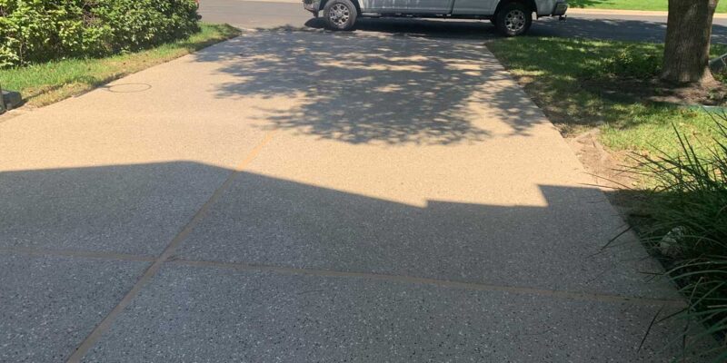 A finely refinished concrete driveway finalized by the Suncoat of Texas team, under tree shade