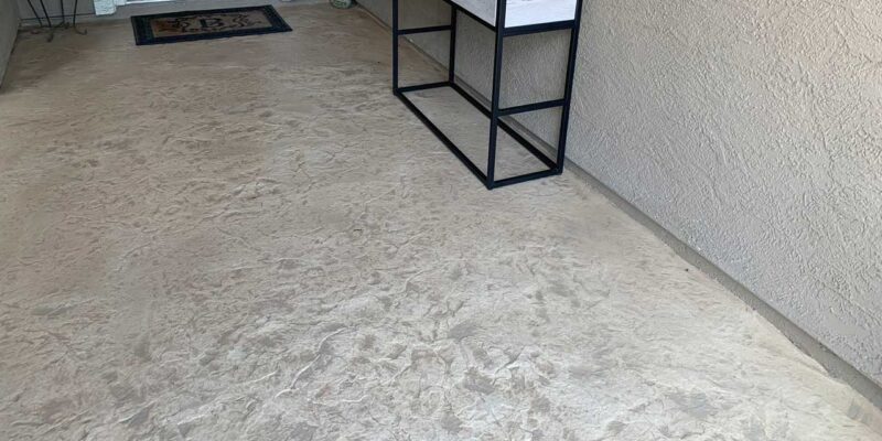 A patio with decorative concrete stamps on the floor and a raised cabinet against the wall.