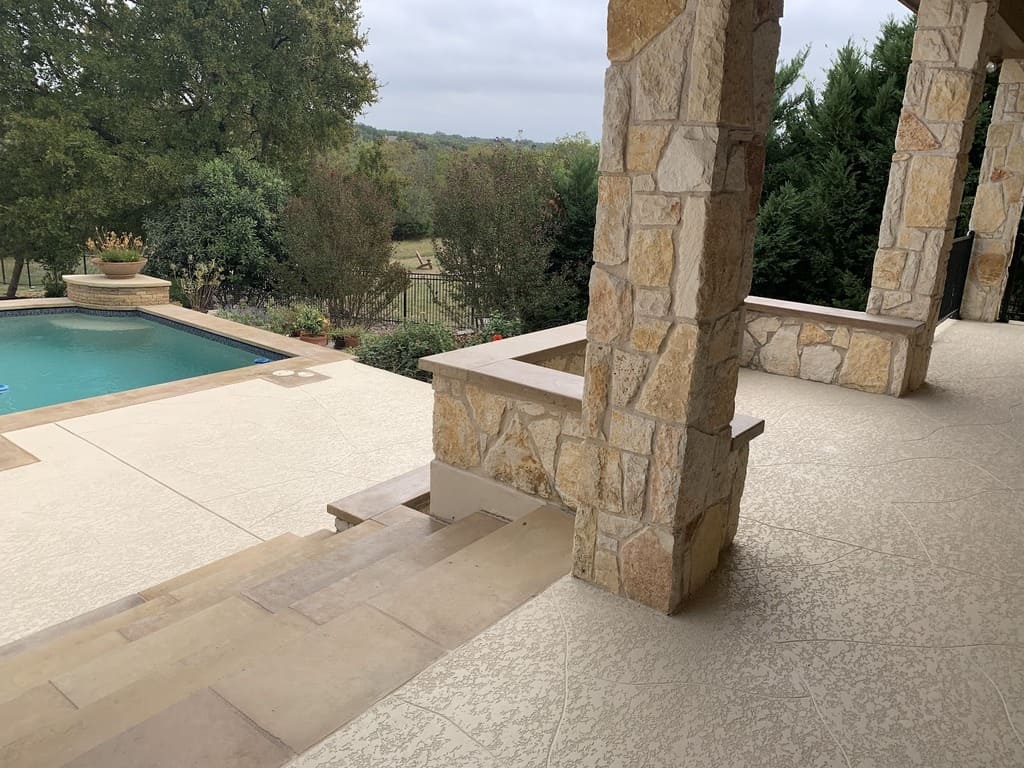 A close-up of a corner of a pool with includes the stairs and the area around the swimming concrete cool deck pool