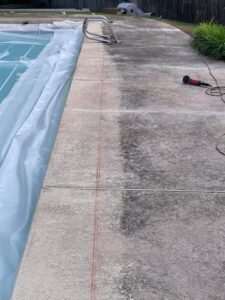 A pool with a gray surface shows signs of erosion under the pool deck and needs repair.