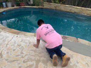 An expert is repairing a cracked section of concrete around the pool with a new material.