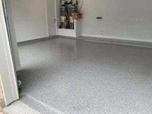 The garage floor, coated in sleek gray epoxy, contrasted beautifully against the white walls.