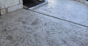 Textured concrete walkway beside stone wall