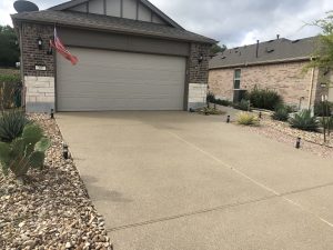 House driveway with American flag and desert plants.