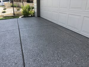 Speckled concrete driveway next to garage door.