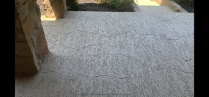 Textured concrete patio with stone wall edge.